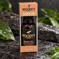 Woody's Shave Oil 1 fl oz with peach-orange carton and gray interior on stone with leaves